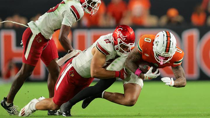 Oct 17, 2025; Miami Gardens, Florida, USA; Miami Hurricanes wide receiver Keelan Marion (0) carries the football against Louisville Cardinals linebacker Kalib Perry (12) during the third quarter at Hard Rock Stadium. Mandatory Credit: Sam Navarro-Imagn Images Oct 17, 2025; Miami Gardens, Florida, USA; Miami Hurricanes wide receiver Keelan Marion (0) carries the football against Louisville Cardinals linebacker Kalib Perry (12) during the third quarter at Hard Rock Stadium. Mandatory Credit: Sam Navarro-Imagn Images