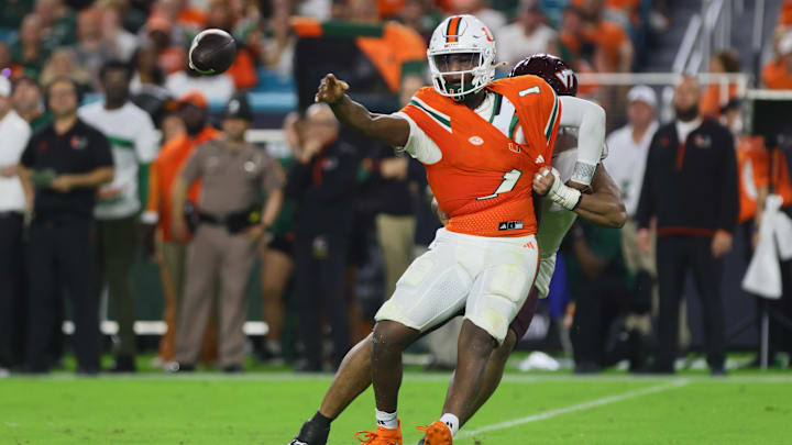Sep 27, 2024; Miami Gardens, Florida, USA; Miami Hurricanes quarterback Cam Ward (1) throws the football as Virginia Tech Hokies defensive lineman Wilfried Pene (91) attempts a tackle during the second quarter at Hard Rock Stadium. Mandatory Credit: Sam Navarro-Imagn Images