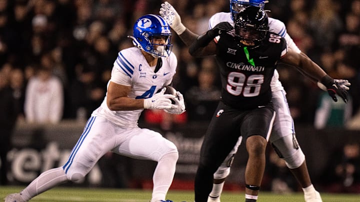 BYU Cougars running back LJ Martin (4) runs for a first down as Cincinnati Bearcats defensive lineman Marquaze Parker (98) defends in the first quarter of the NCAA football game at Nippert Stadium in Cincinnati on Nov. 22, 2025.