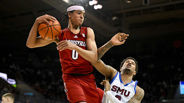 Feb 17, 2026; Dallas, Texas, USA; Louisville Cardinals guard Mikel Brown Jr. (0) grabs a rebound in front of SMU Mustangs forward Corey Washington (3) during the second half at Moody Coliseum. Mandatory Credit: Jerome Miron-Imagn Images