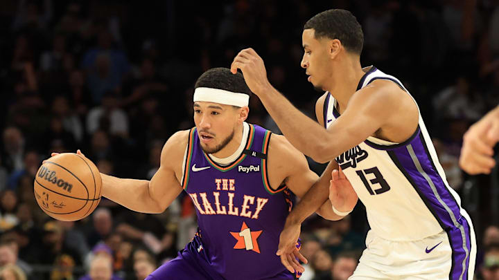 Mar 14, 2025; Phoenix, Arizona, USA; Phoenix Suns guard Devin Booker (1) dribbles the ball past Sacramento Kings forward Keegan Murray (13) during the first half at Footprint Center. Mandatory Credit: Mark J. Rebilas-Imagn Images