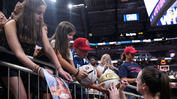 Indiana Fever guard Caitlin Clark (22) signs a basketball for a fan following a game against the Seattle Storm on Sunday, Aug. 18, 2024, at Gainbridge Fieldhouse in Indianapolis. The Fever defeated the Storm 92-75.