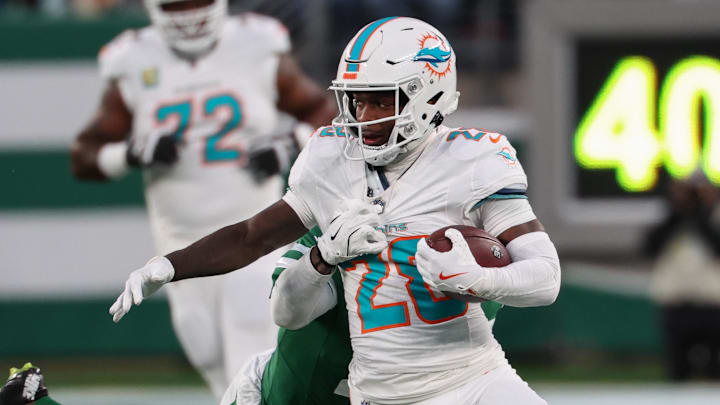 Jan 5, 2025; East Rutherford, New Jersey, USA; Miami Dolphins running back De'Von Achane (28) runs with the ball while New York Jets cornerback D.J. Reed (4) attempts to tackle him during the first quarter at MetLife Stadium. Mandatory Credit: Ed Mulholland-Imagn Images