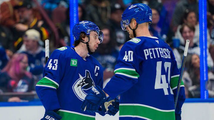 Vancouver Canucks defenseman Quinn Hughes talks with forward Elias Pettersson during a stoppage against the Winnipeg Jets.