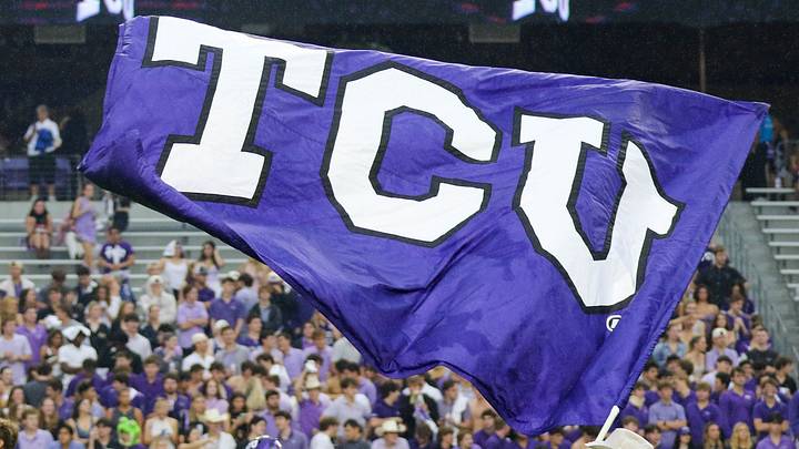 A purple TCU flag waves above fans in the stands at Amon G. Carter Stadium. A purple TCU flag waves above fans in the stands at Amon G. Carter Stadium.