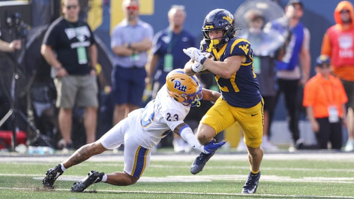 Sep 13, 2025; Morgantown, West Virginia, USA; West Virginia Mountaineers running back Clay Ash (27) catches a pass and runs for extra yards as Pittsburgh Panthers defensive back Davion Pritchard (23) tackles during the second quarter at Milan Puskar Stadium. Mandatory Credit: Ben Queen-Imagn Images