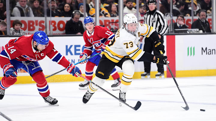 Jan 24, 2026; Boston, Massachusetts, USA; Montreal Canadiens center Nick Suzuki (14) tries to poke the puck from Boston Bruins defenseman Charlie McAvoy (73) during the third period at TD Garden. Mandatory Credit: Bob DeChiara-Imagn Images