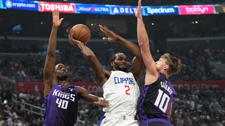 Feb 25, 2024; Los Angeles, California, USA; LA Clippers forward Kawhi Leonard (2) guarded by Sacramento Kings forward Harrison Barnes (40) and center Domanats Sabonis (10).