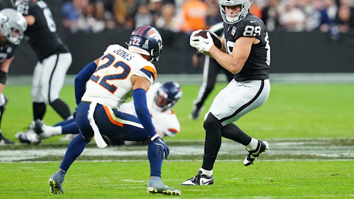 Nov 24, 2024; Paradise, Nevada, USA; Las Vegas Raiders tight end Brock Bowers (89) looks to evade the tackle of Denver Broncos safety Brandon Jones (22) during the fourth quarter at Allegiant Stadium. Mandatory Credit: Stephen R. Sylvanie-Imagn Images