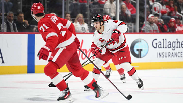 Apr 4, 2025; Detroit, Michigan, USA; Carolina Hurricanes center Justin Robidas (46) brings the puck up ice against Detroit Red Wings center Dylan Larkin (71) during the first period at Little Caesars Arena. Mandatory Credit: Tim Fuller-Imagn Images
