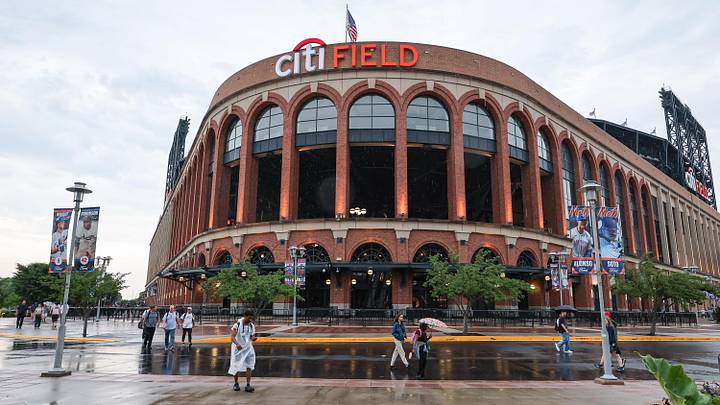 Jul 1, 2025; New York City, New York, USA; Fans walk in the rain out side Citi Field. The game between the New York Mets and the Milwaukee Brewers was postponed due to impending weather.  Mandatory Credit: Vincent Carchietta-Imagn Images