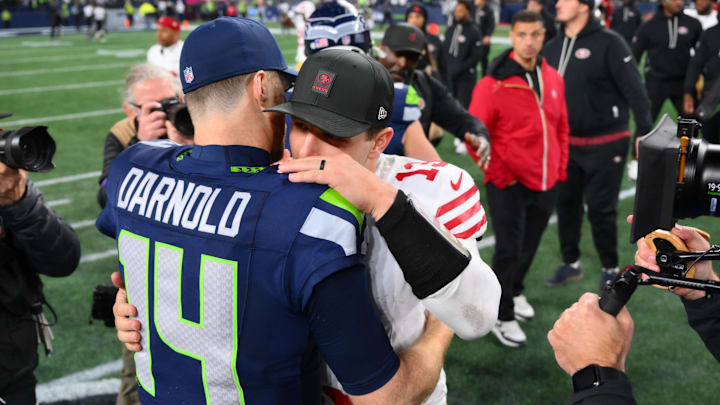 Jan 17, 2026; Seattle, WA, USA; Seattle Seahawks quarterback Sam Darnold (14) and San Francisco 49ers quarterback Brock Purdy (13) talk following an NFC Divisional Round game at Lumen Field.