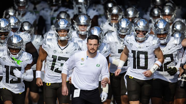 Nov 18, 2023; Tempe, Arizona, USA; Oregon Ducks head coach Dan Lanning (center) leads quarterback Bo Nix (10) and Ty Thompson (13) onto the field for the game against the Arizona State Sun Devils at Mountain America Stadium. Mandatory Credit: Mark J. Rebilas-Imagn Images Nov 18, 2023; Tempe, Arizona, USA; Oregon Ducks head coach Dan Lanning (center) leads quarterback Bo Nix (10) and Ty Thompson (13) onto the field for the game against the Arizona State Sun Devils at Mountain America Stadium. Mandatory Credit: Mark J. Rebilas-Imagn Images