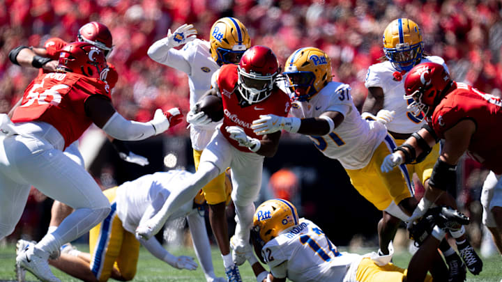 Cincinnati Bearcats wide receiver Tyrin Smith (4) runs for a first down as Pittsburgh Panthers defensive lineman David Ojiegbe (17) and Pittsburgh Panthers linebacker Rasheem Biles (31) tackle him in the second quarter of the College Football game at Nippert Stadium in Cincinnati on Saturday, Sept. 7, 2024.