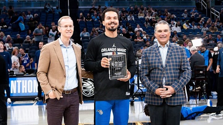 Orlando Magic president of basketball operations Jeff Weltman, guard Cole Anthony and CEO Alex Martins pose as Anthony is presented his Bob Lanier Community Assist Award.