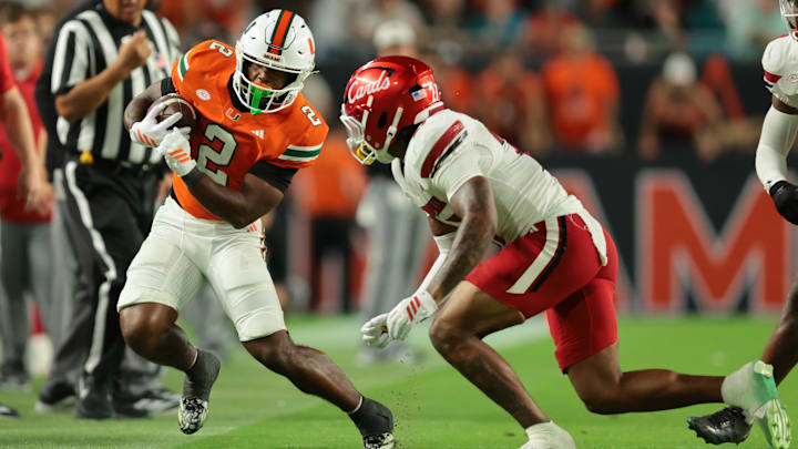 Oct 17, 2025; Miami Gardens, Florida, USA; Miami Hurricanes running back Jordan Lyle (2) runs out of bounds as Louisville Cardinals defensive back Jojo Evans Jr. (27) defends during the fourth quarter at Hard Rock Stadium. Mandatory Credit: Sam Navarro-Imagn Images