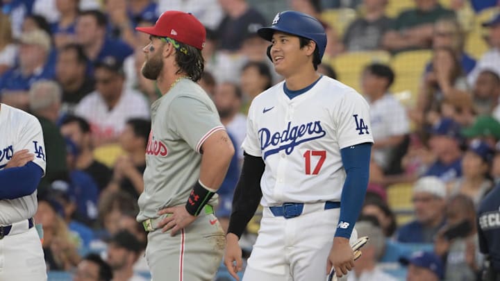 Aug 7, 2024; Los Angeles, California, USA;  Los Angeles Dodgers designated hitter Shohei Ohtani (17) laughs with Philadelphia Phillies first baseman Bryce Harper (3) as they wait for a replay in the first inning at Dodger Stadium. Mandatory Credit: Jayne Kamin-Oncea-Imagn Images