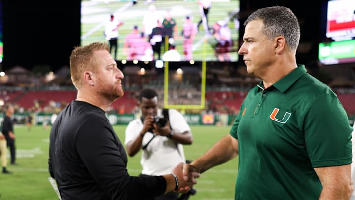 Sep 21, 2024; Tampa, Florida, USA;  Miami Hurricanes head coach Mario Cristobal greet South Florida Bulls head coach Alex Goulash after a game at Raymond James Stadium. Mandatory Credit: Nathan Ray Seebeck-Imagn Images