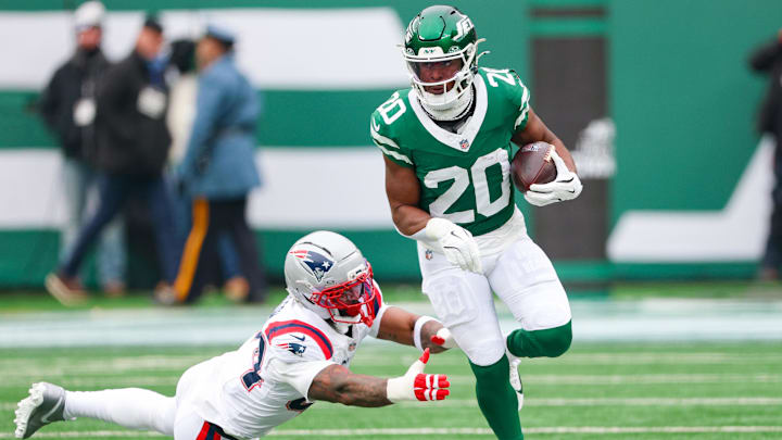 Dec 28, 2025; East Rutherford, New Jersey, USA; New York Jets running back Breece Hall (20) carries the ball asNew England Patriots linebacker K'Lavon Chaisson (44) pursues during the first half at MetLife Stadium. Mandatory Credit: Vincent Carchietta-Imagn Images
