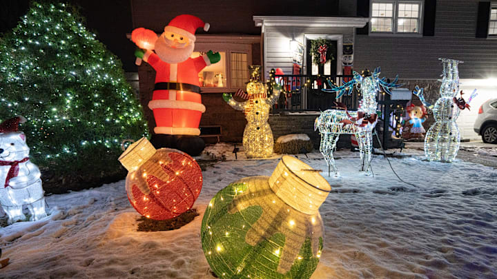 Large Christmas tree ornaments shine in the front yard of a house 