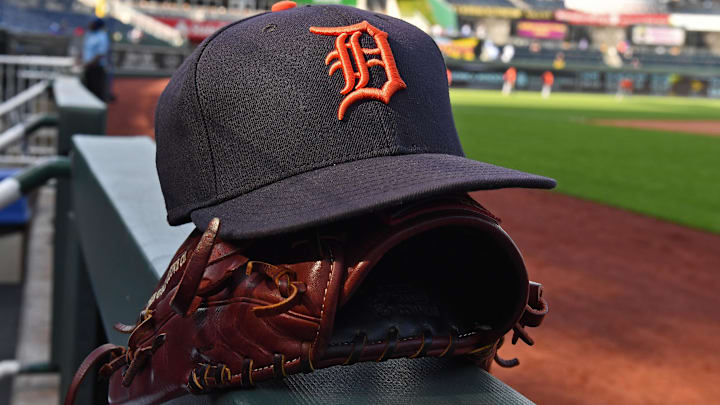 A Detroit Tigers cap and glove on the dugout railing.