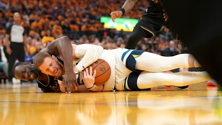 May 12, 2025; San Francisco, California, USA; Minnesota Timberwolves guard Donte DiVincenzo (0) gains control of a loose ball next to Golden State Warriors forward Draymond Green (23) in the second quarter during game four of the second round for the 2025 NBA Playoffs at Chase Center. Mandatory Credit: Cary Edmondson-Imagn Images