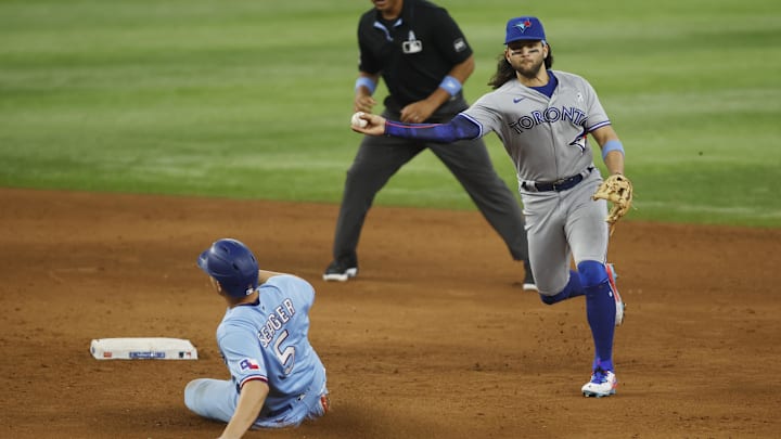 Jun 18, 2023; Arlington, Texas, USA; Toronto Blue Jays shortstop Bo Bichette (11) turns a double play in the fifth inning as Texas Rangers shortstop Corey Seager (5) slides into second base at Globe Life Field. Mandatory Credit: Tim Heitman-Imagn Images