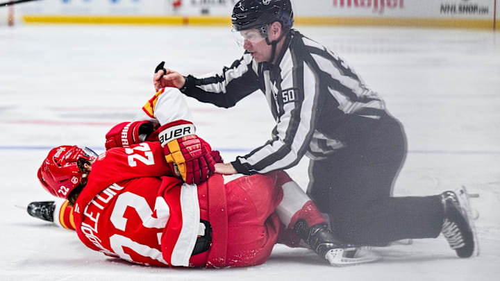 Mar 16, 2026; Detroit, Michigan, USA; Detroit Red Wings center Mason Appleton (22) and Calgary Flames center Connor Zary (47) are broken up by linesman Scott Cherrey (50) during the second period at Little Caesars Arena. Mandatory Credit: Tim Fuller-Imagn Images
