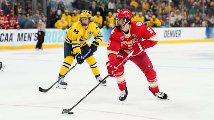 Apr 9, 2026; Las Vegas, Nevada, UNITED STATES; Denver Pioneers defenseman Garrett Brown (5) moves the puck in  overtime against the Michigan Wolverines in the semifinals of the NCAA men's ice hockey Frozen Four at T-Mobile Arena. Mandatory Credit: Lucas Peltier-Imagn Images