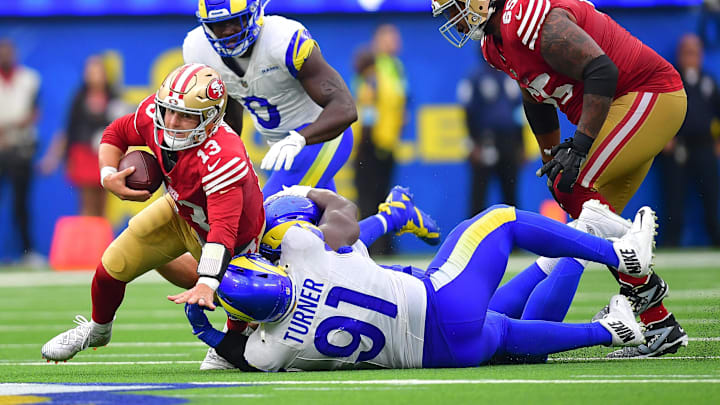 Sep 22, 2024; Inglewood, California, USA; San Francisco 49ers quarterback Brock Purdy (13) is brought down by Los Angeles Rams defensive tackle Braden Fiske (55) and defensive tackle Kobie Turner (91) during the second half at SoFi Stadium. Mandatory Credit: Gary A. Vasquez-Imagn Images