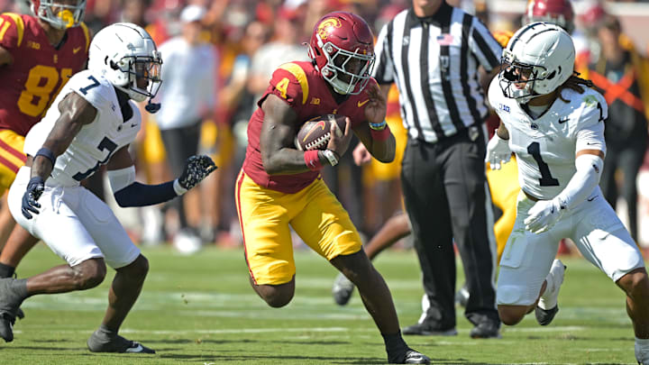 Oct 12, 2024; Los Angeles, California, USA; USC Trojans running back Woody Marks (4) runs the ball for a first down before he is stopped by Penn State Nittany Lions safety Jaylen Reed (1) and cornerback Zion Tracy (7) in the first half at United Airlines Field at the Los Angeles Memorial Coliseum. Mandatory Credit: Jayne Kamin-Oncea-Imagn Images