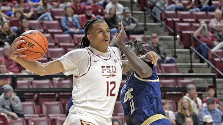 Jan 18, 2025; Tallahassee, Florida, USA;  Florida State Seminoles forward Malique Ewin (12) drives the ball past Georgia Tech Yellowjackets forward Baye Ndongo (11) during the first half at Donald L. Tucker Center. Mandatory Credit: Robert Myers-Imagn Images