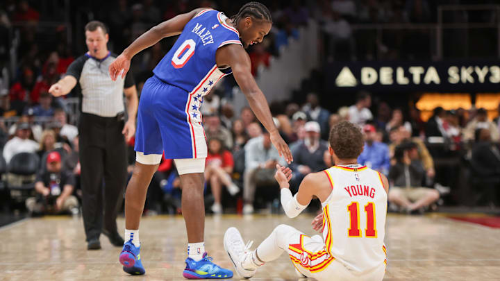 Oct 14, 2024; Atlanta, Georgia, USA; Philadelphia 76ers guard Tyrese Maxey (0) helps Atlanta Hawks guard Trae Young (11) up in the second quarter at State Farm Arena. Mandatory Credit: Brett Davis-Imagn Images