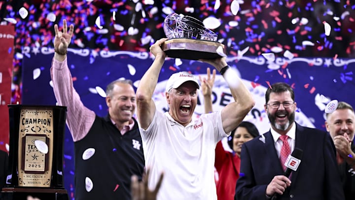 Dec 27, 2025; Houston, TX, USA; Houston Cougars head coach Willie Fritz hoists the champions trophy after the win over Louisiana State Tigers at NRG Stadium. Mandatory Credit: Maria Lysaker-Imagn Images 