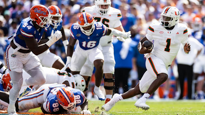 Aug 31, 2024; Gainesville, Florida, USA; Miami Hurricanes quarterback Cam Ward (1) breaks a tackle against Florida Gators defensive lineman Caleb Banks (88) and defensive end Tyreak Sapp (94) during the first half at Ben Hill Griffin Stadium. Mandatory Credit: Matt Pendleton-Imagn Images