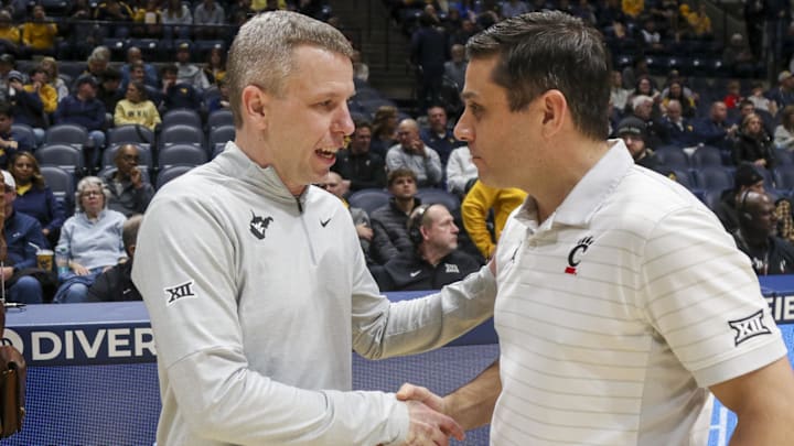 Jan 6, 2026; Morgantown, West Virginia, USA; West Virginia Mountaineers head coach Ross Hodge talks with Cincinnati Bearcats head coach Wes Miller before the game at Hope Coliseum. Mandatory Credit: Ben Queen-Imagn Images Jan 6, 2026; Morgantown, West Virginia, USA; West Virginia Mountaineers head coach Ross Hodge talks with Cincinnati Bearcats head coach Wes Miller before the game at Hope Coliseum. Mandatory Credit: Ben Queen-Imagn Images