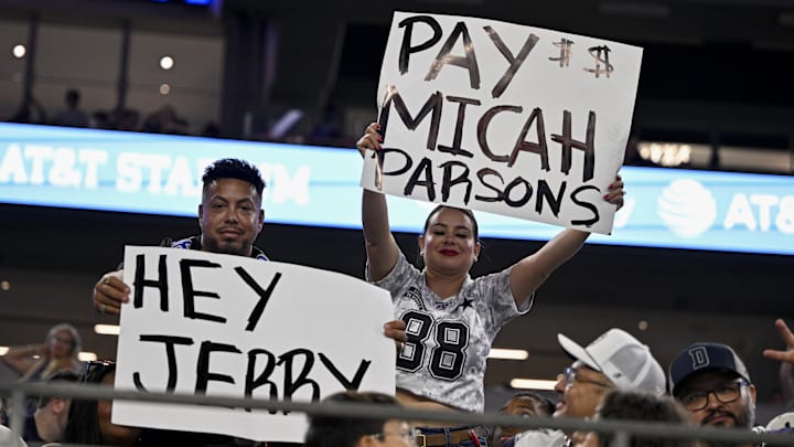 Dallas Cowboys fans hold up signs to owner Jerry Jones and defensive end Micah Parsons. Dallas Cowboys fans hold up signs to owner Jerry Jones and defensive end Micah Parsons.