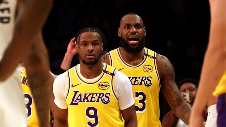 Oct 22, 2024; Los Angeles, California, USA; Los Angeles Lakers forward LeBron James (23) checks into the game with his son, guard Bronny James (9) during the second quarter against the Minnesota Timberwolves at Crypto.com Arena. This marked the first time in NBA history that a father and son played together. Mandatory Credit: Jason Parkhurst-Imagn Images