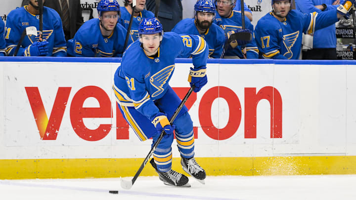 Apr 5, 2025; St. Louis, Missouri, USA;  St. Louis Blues right wing Jimmy Snuggerud (21) controls the puck against the Colorado Avalanche during the second period at Enterprise Center. Mandatory Credit: Jeff Curry-Imagn Images