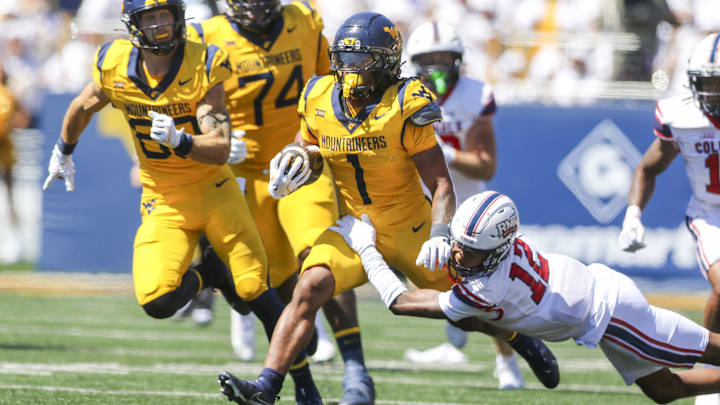Aug 30, 2025; Morgantown, West Virginia, USA; West Virginia Mountaineers running back Jahiem White (1) runs the ball and is tackled by Robert Morris Colonials quarterback Jake Wolfe (12) during the first quarter at Milan Puskar Stadium. Mandatory Credit: Ben Queen-Imagn Images