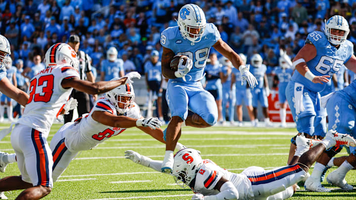 Oct 7, 2023; Chapel Hill, North Carolina, USA; North Carolina Tar Heels running back Omarion Hampton (28) leaps over Syracuse Orange players during the first half of the game at Kenan Memorial Stadium. 