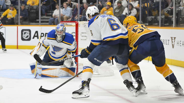 Mar 27, 2025; Nashville, Tennessee, USA;  St. Louis Blues goaltender Joel Hofer (30) and defenseman Philip Broberg (6) blocks the shot of Nashville Predators left wing Michael Bunting (58) during the third period at Bridgestone Arena. Mandatory Credit: Steve Roberts-Imagn Images