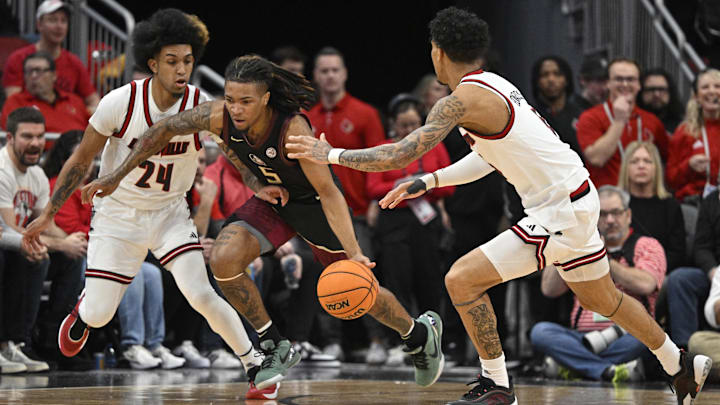 Feb 22, 2025; Louisville, Kentucky, USA;  Florida State Seminoles guard Daquan Davis (5) dribbles against Louisville Cardinals guard Chucky Hepburn (24) and guard Terrence Edwards Jr. (5) during the first half at KFC Yum! Center. Mandatory Credit: Jamie Rhodes-Imagn Images