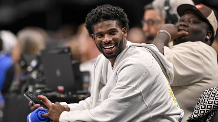 Jan 14, 2025; Dallas, Texas, USA; Colorado Buffaloes quarterback Shedeur Sanders laughs as he watches the game between the Dallas Mavericks and the Denver Nuggets during the second half at the American Airlines Center. Mandatory Credit: Jerome Miron-Imagn Images