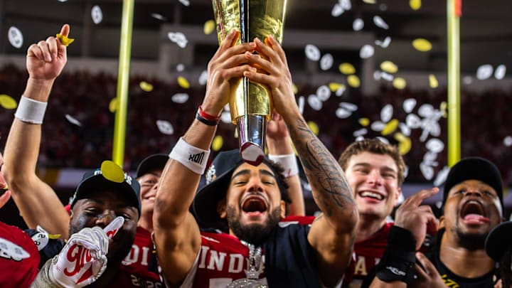 Indiana's Elijah Sarratt (13) lifts the trophy as Tyrique Tucker (95), Charlie Becker (80), Fernando Mendoza (15), and Mikail Kamara (6) celebrate on the podium after the College Football Playoff National Championship college football game at Hard Rock Stadium in Miami Gardens on Monday, Jan. 19, 2026.
