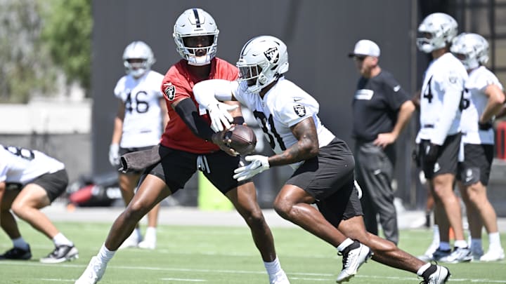 Jun 10, 2025; Henderson, NV, USA; Las Vegas Raiders quarterback Geno Smith (7) hands the ball off to running back Raheem Mostert (31) during a drill at Las Vegas Raiders Minicamp at Intermountain Health Performance Center. Mandatory Credit: Candice Ward-Imagn Images
