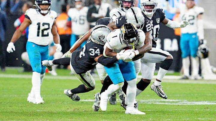 Dec 22, 2024; Paradise, Nevada, USA; Jacksonville Jaguars running back Travis Etienne Jr. (1) is tackled by Las Vegas Raiders safety Thomas Harper (34) and cornerback Decamerion Richardson (25) during the fourth quarter at Allegiant Stadium. Mandatory Credit: Stephen R. Sylvanie-Imagn Images Dec 22, 2024; Paradise, Nevada, USA; Jacksonville Jaguars running back Travis Etienne Jr. (1) is tackled by Las Vegas Raiders safety Thomas Harper (34) and cornerback Decamerion Richardson (25) during the fourth quarter at Allegiant Stadium. Mandatory Credit: Stephen R. Sylvanie-Imagn Images