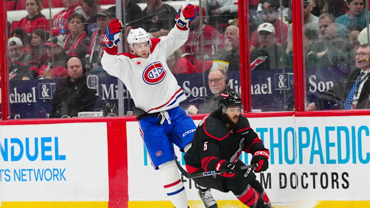 Mar 28, 2025; Raleigh, North Carolina, USA;  Montreal Canadiens right wing Josh Anderson (17) side steps a check by Carolina Hurricanes defenseman Jalen Chatfield (5) during the second period at Lenovo Center. Mandatory Credit: James Guillory-Imagn Images