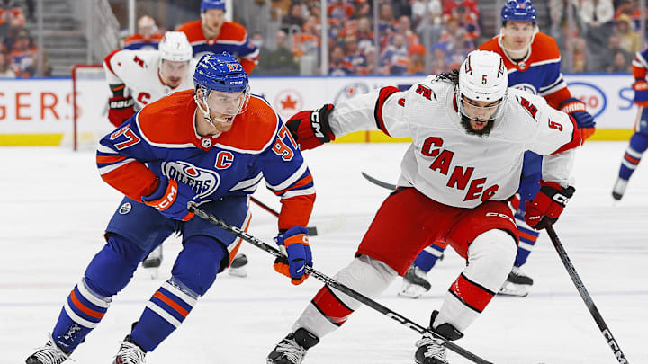 Dec 6, 2023; Edmonton, Alberta, CAN; Edmonton Oilers forward Connor McDavid (97) battles for position with Carolina Hurricanes defensemen Jalen Catfield (5) during the third period at Rogers Place. Mandatory Credit: Perry Nelson-Imagn Images