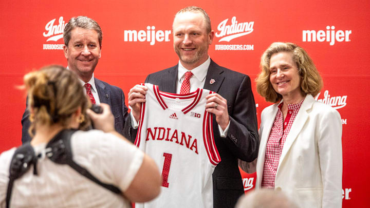 Indiana University Vice President and Director of Intercollegiate Athletics Scott Dolson, Indiana University men's basketball Head Coach Darian DeVries and Indiana University President Pamela Whitten pose with a jersey at the introductory press conference at Simon Skjodt Assembly Hall on Wednesday, March 19, 2025.